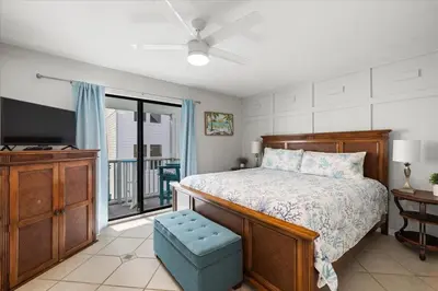 a bedroom with a bed and a tv and a balcony at Paradise found steps to beach in Panama City Beach