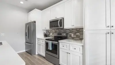 a kitchen with white cabinets and a black appliances at PCB 3 Bed 2 Bath house Chasing Sunsets in Panama City Beach