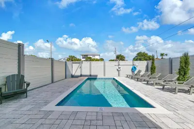 a swimming pool with chairs and a fence at Golden Seashell East in Panama City Beach