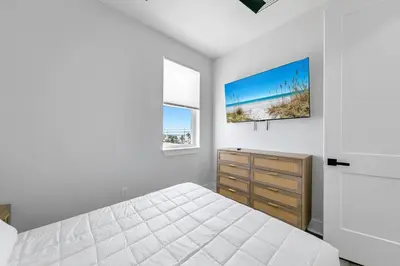 a white bedroom with a bed and a dresser at Golden Seashell East in Panama City Beach