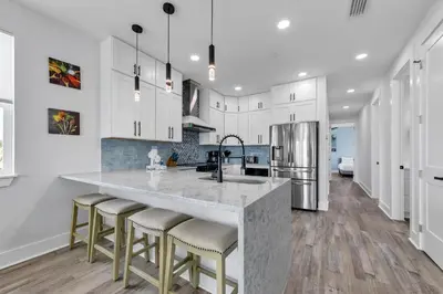 a kitchen with white cabinets and a large island with bar stools at Golden Seashell West in Panama City Beach