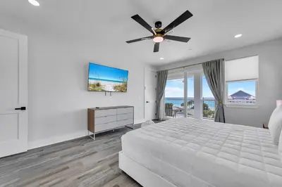 a white bedroom with a bed and a ceiling fan at Golden Seashell West in Panama City Beach
