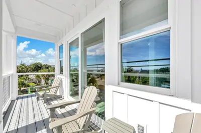 a porch with chairs and windows on a white house at Golden Seashell West in Panama City Beach