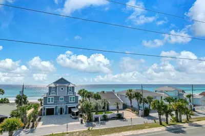 a house on the beach with palm trees and the ocean at Golden Seashell West in Panama City Beach