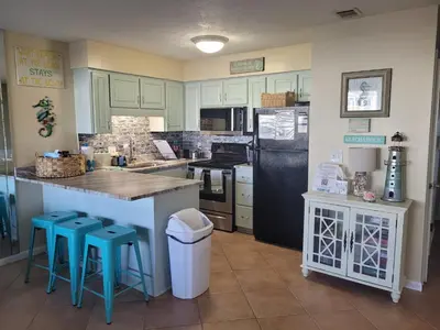 a kitchen with a black refrigerator and blue stools at Southwinds I-5 in Panama City Beach