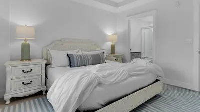 a white bedroom with a bed and two night stands at 429 S Bridge Ln 107A in Watersound Beach