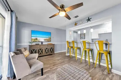 a living room with yellow chairs and a ceiling fan at Endless Summer D5 in Panama City Beach