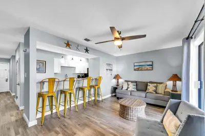 a living room with yellow chairs and a couch at Endless Summer D5 in Panama City Beach