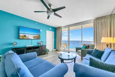 a living room with blue furniture and a flat screen tv at Majestic Beach Towers 2-1801 in Panama City Beach