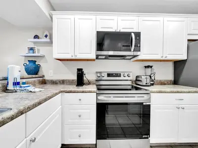a white kitchen with white cabinets and a microwave at Edgewater Golf Villa 3204 in Panama City Beach
