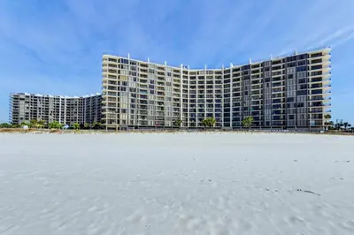 a large building on the beach next to the sand at Edgewater Golf Villa 3204 in Panama City Beach