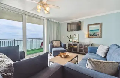 a living room with blue furniture and a large window at Fabulous Views at Emerald Beach in Panama City Beach