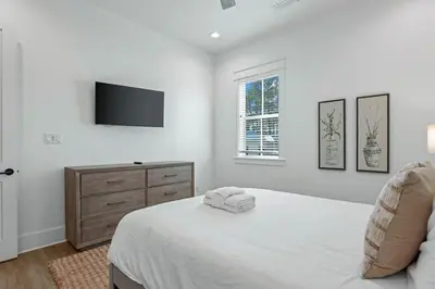 a white bedroom with a bed and a tv at Serenity at Treetop in Inlet Beach