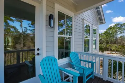 two blue chairs sitting on the front porch of a house at Serenity at Treetop in Inlet Beach