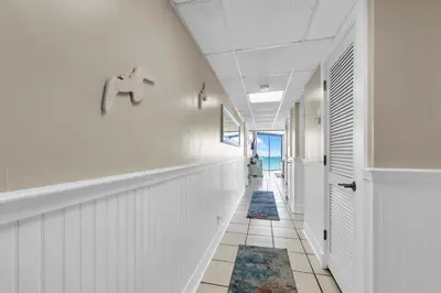 a hallway with white walls and a hallway with blue rugs at Leeward 403 at Edgewater in Panama City Beach
