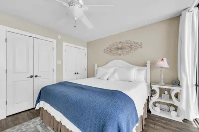 a bedroom with a large bed with a blue blanket at Leeward 403 at Edgewater in Panama City Beach