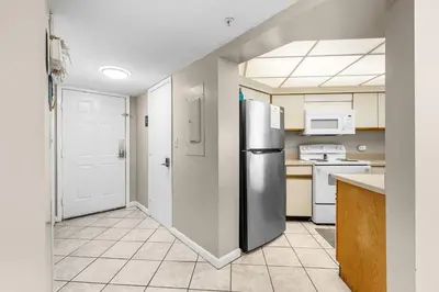a kitchen with a stainless steel refrigerator and white appliances at East-End PCB Condo with Gulf Views & Beach Access in Panama City Beach