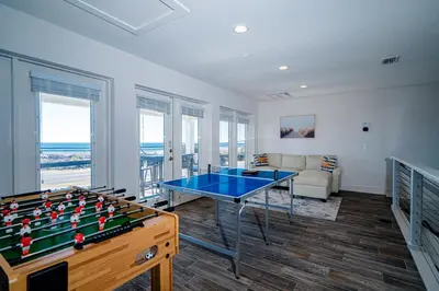 a living room with a ping pong table and a couch at Private Beach, Heated Pool, Gulf Beach Front in Panama City Beach