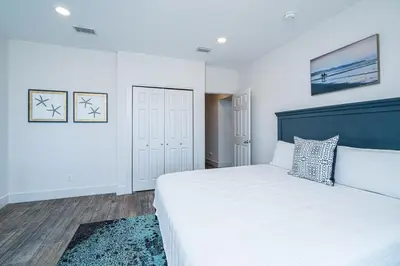 a bedroom with a white bed with a blue headboard at Private Beach, Heated Pool, Gulf Beach Front in Panama City Beach