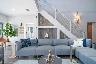 a living room with a blue couch and a staircase at Private Beach, Heated Pool, Gulf Beach Front in Panama City Beach