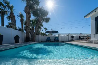 a swimming pool with two chairs and an umbrella at Private Beach, Heated Pool, Gulf Beach Front in Panama City Beach
