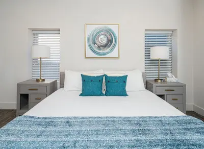 a bedroom with a white bed with blue pillows at Private Beach, Heated Pool, Gulf Beach Front in Panama City Beach