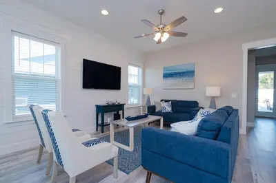 a living room with a blue couch and a tv at Brand New, Steps To Beach, Gulf Views, Heated Pool in Panama City Beach