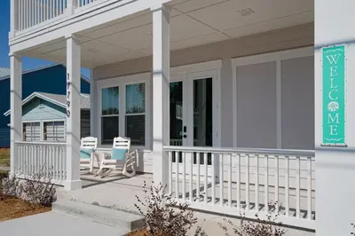 a house with a porch with two chairs on it at Brand New, Steps To Beach, Gulf Views, Heated Pool in Panama City Beach