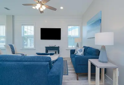 a living room with two blue couches and a tv at Brand New, Steps To Beach, Gulf Views, Heated Pool in Panama City Beach