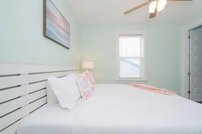 a white bedroom with a large white bed with pillows at Brand New, Steps To Beach, Gulf Views, Heated Pool in Panama City Beach