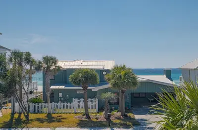 a house with palm trees in front of the ocean at Brand New, Steps To Beach, Gulf Views, Heated Pool in Panama City Beach