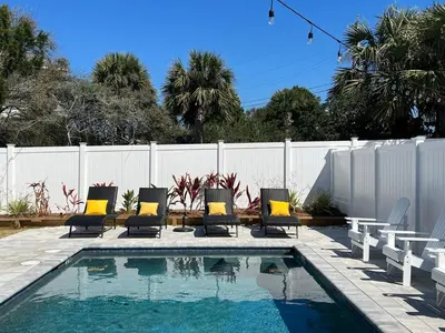 a swimming pool with chairs and a fence and a fence at Brand New, Steps To Beach, Gulf Views, Heated Pool in Panama City Beach
