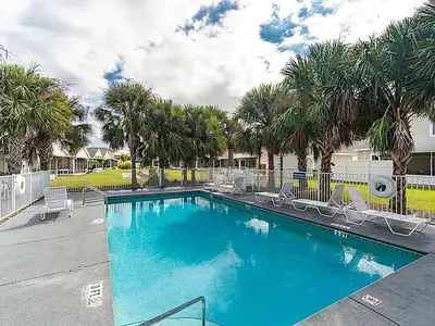 a swimming pool with chairs and palm trees at High Tides by Emerald Coast Retreats in Panama City Beach