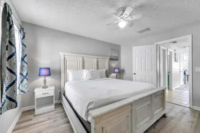 a bedroom with a white bed and a ceiling fan at High Tides by Emerald Coast Retreats in Panama City Beach