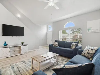 a living room with a blue couch and a tv at High Tides by Emerald Coast Retreats in Panama City Beach