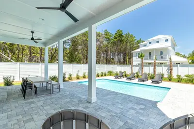 a patio with a table and chairs next to a swimming pool at Brand New, Private Pool, Walk To Beach, Game Room in Inlet Beach