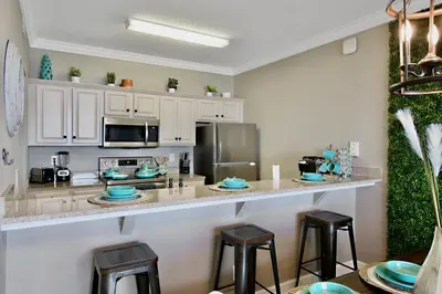 a kitchen with white cabinets and a counter with stools at Beachfront Bliss at Ocean Ritz! 3BR 3BA! Sleeps 10 by Dolce Vita Getaways PCB in Panama City Beach