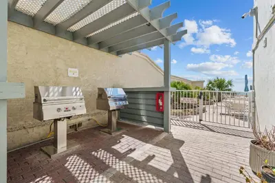 a grill and smoker on a patio with a fence at Beachfront Bliss at Ocean Ritz! 3BR 3BA! Sleeps 10 by Dolce Vita Getaways PCB in Panama City Beach