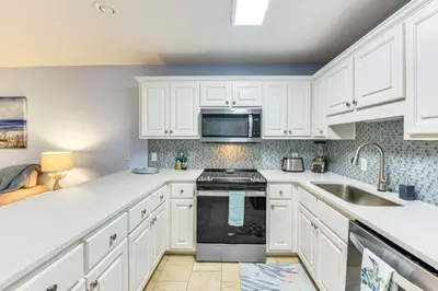 a kitchen with white cabinets and a sink at Walk to Pool and Beach PCB Resort Getaway with Porch in Panama City Beach