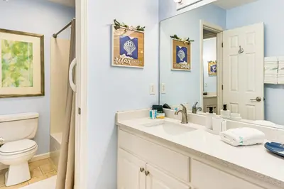 a bathroom with a sink and a toilet and a mirror at Walk to Pool and Beach PCB Resort Getaway with Porch in Panama City Beach