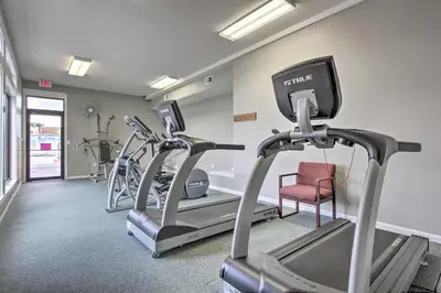 a gym with two treadmill machines and a red chair at Walk to Pool and Beach PCB Resort Getaway with Porch in Panama City Beach