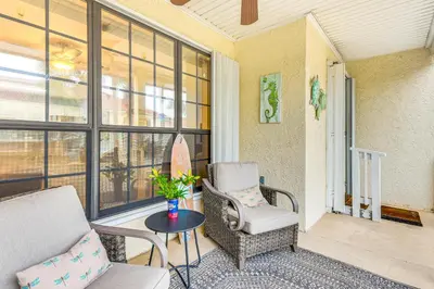 a porch with a chair and a table and a surfboard at Walk to Pool and Beach PCB Resort Getaway with Porch in Panama City Beach
