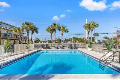 a swimming pool with chairs and palm trees at Ocean Breeze 1A in Panama City Beach