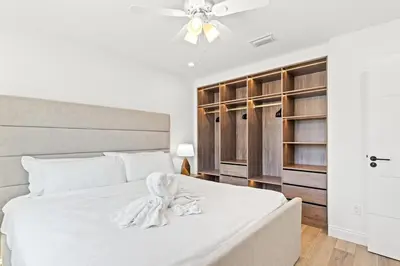 a bedroom with a white bed with a ceiling fan at Ocean Breeze 1B in Panama City Beach