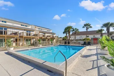 a swimming pool in a resort with palm trees at Ocean Breeze 1B in Panama City Beach