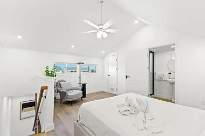 a white bedroom with a bed and a chair at Ocean Breeze 2C in Panama City Beach