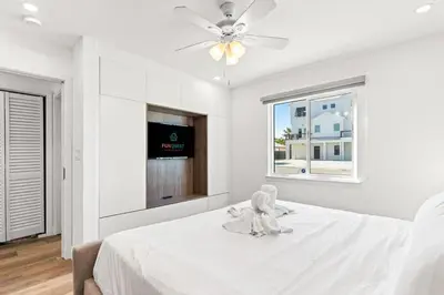 a white bedroom with a stuffed animal sitting on a bed at Ocean Breeze 2B in Panama City Beach