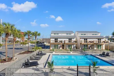 a swimming pool with chairs and a building at Ocean Breeze 2D in Panama City Beach