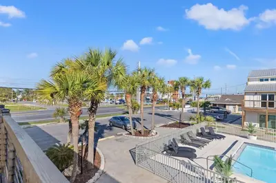 a balcony with a pool and palm trees at Ocean Breeze 3C in Panama City Beach