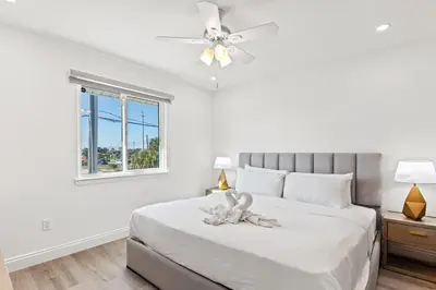 a white bedroom with a bed with a ceiling fan at Ocean Breeze 3D in Panama City Beach